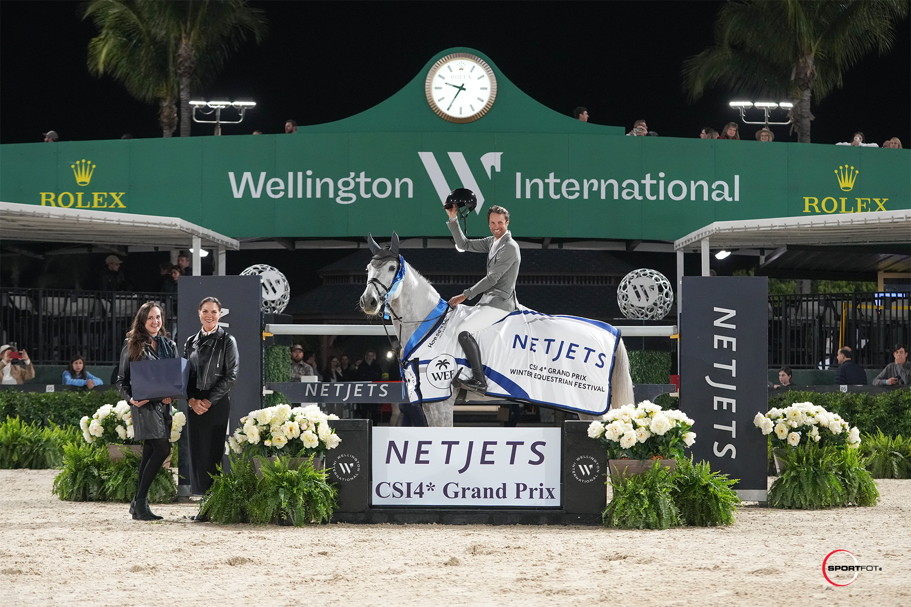 Christian Kukuk & Checker 47 are presented as winners of the NetJets CSI4* Grand Prix by (left to right) Melissa Dombro, VP of Sales for NetJets and Laura Southard, Senior Manager of Strategic Partnerships for NetJets. Photo © Sportfot